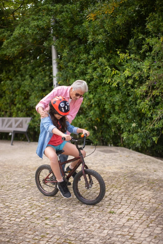 a man helps a little girl learn how to ride a bike