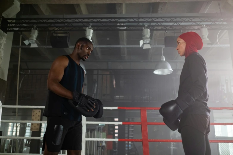 two men in black are talking and holding helmets