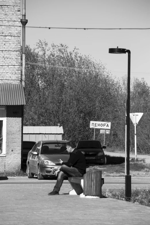 man is sitting on a curb next to a van