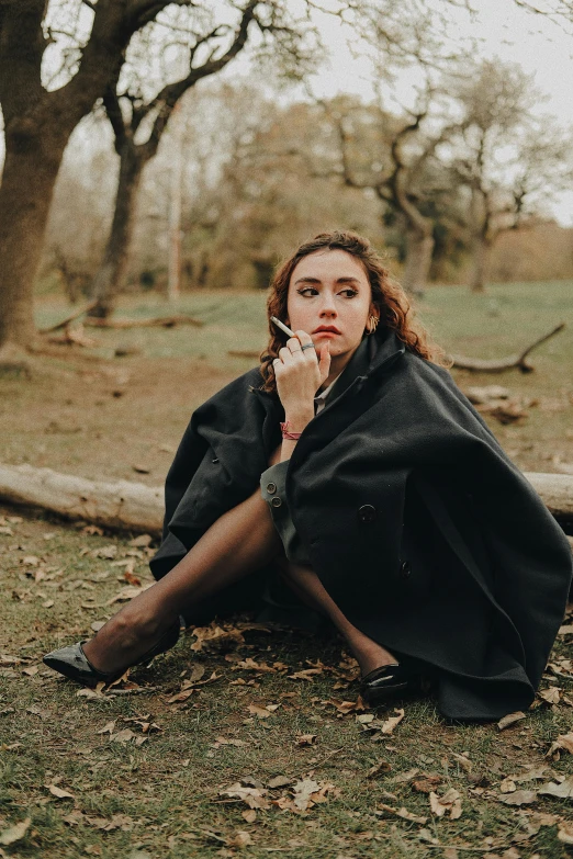 a person sitting on a leaf covered ground and looking at soing