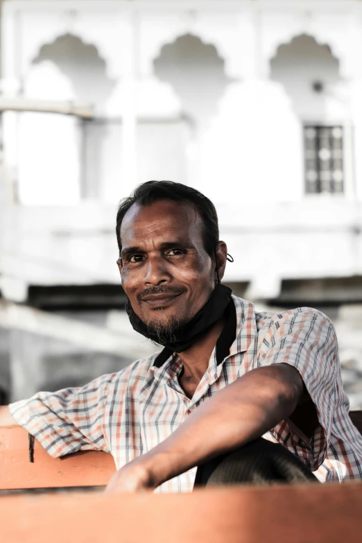 a man is sitting in the shade and has a white house in the background