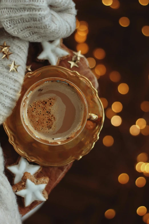 a person holding a cup of coffee near a christmas tree