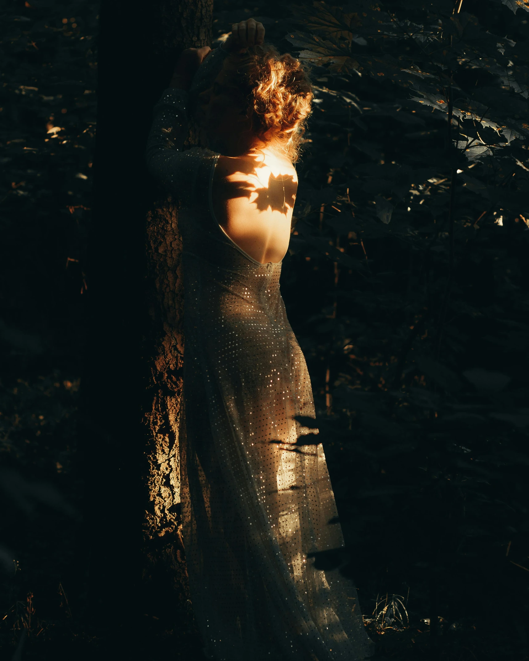 a woman standing in the dark near a tree