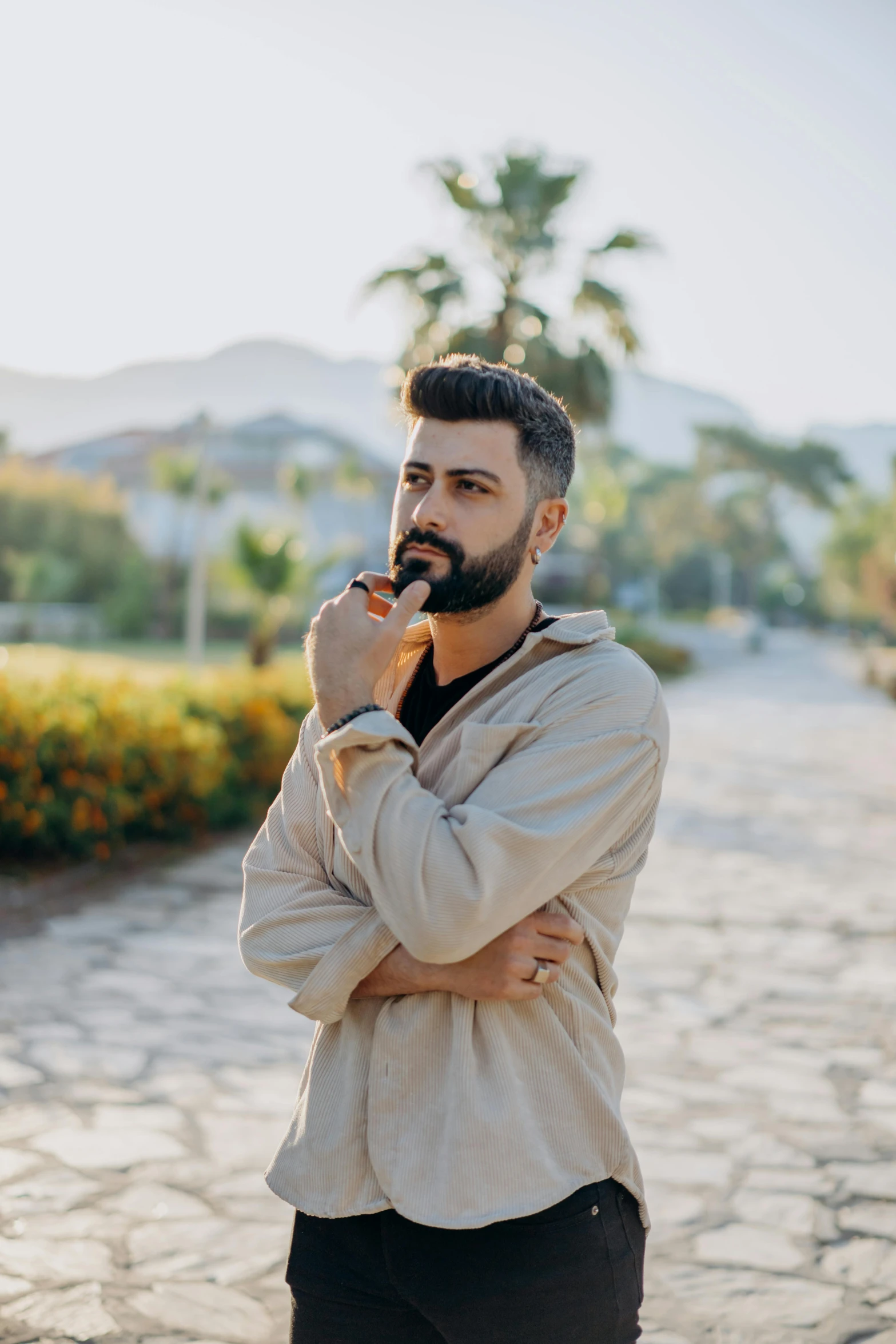 man standing with arms crossed while talking on cell phone