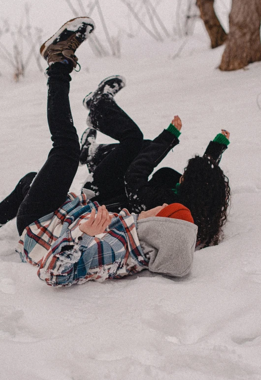 two people lying in the snow one with his feet on another with their skis on