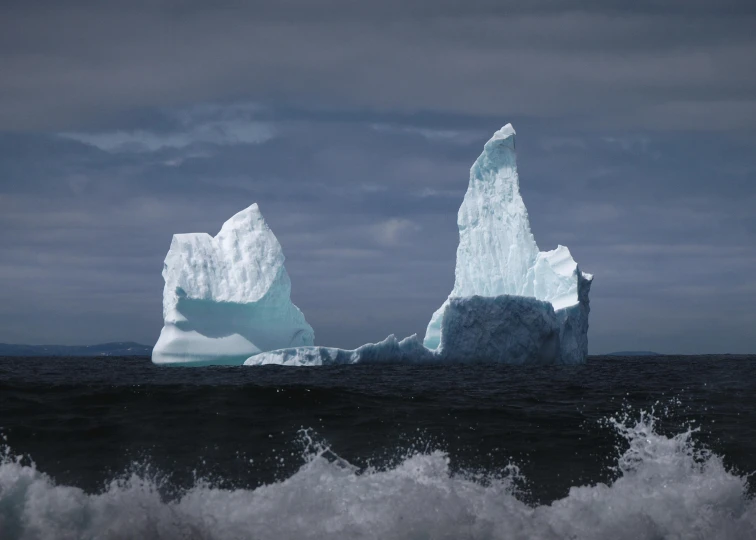 large iceberg in ocean against stormy sky