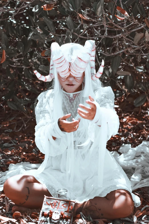 girl with demon horns and white clothes in a field of leaves