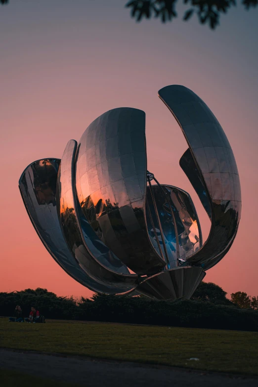 the sun sets behind the sculpture which looks like a huge leaf