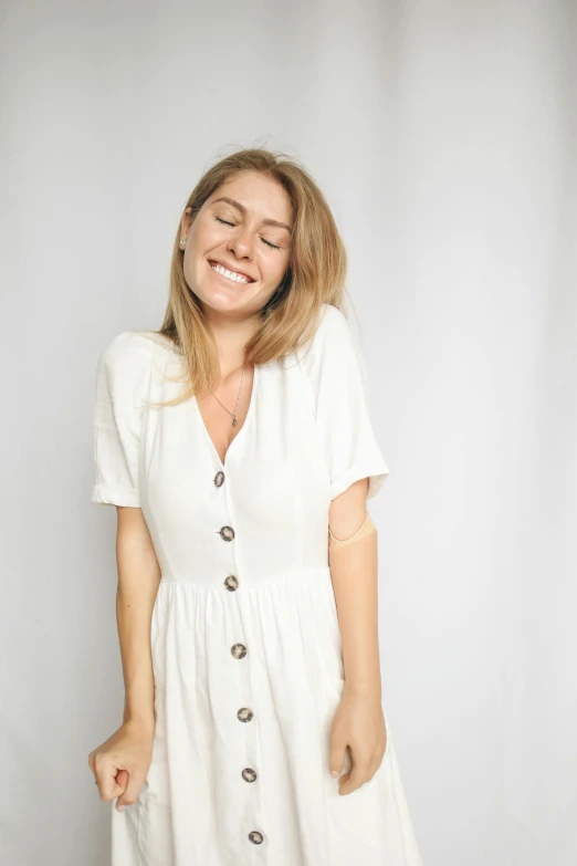 a smiling blonde woman is wearing a white dress