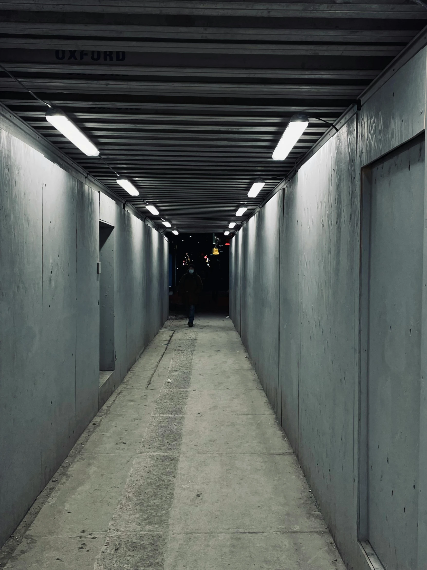 a long hallway with dark light and cement walls