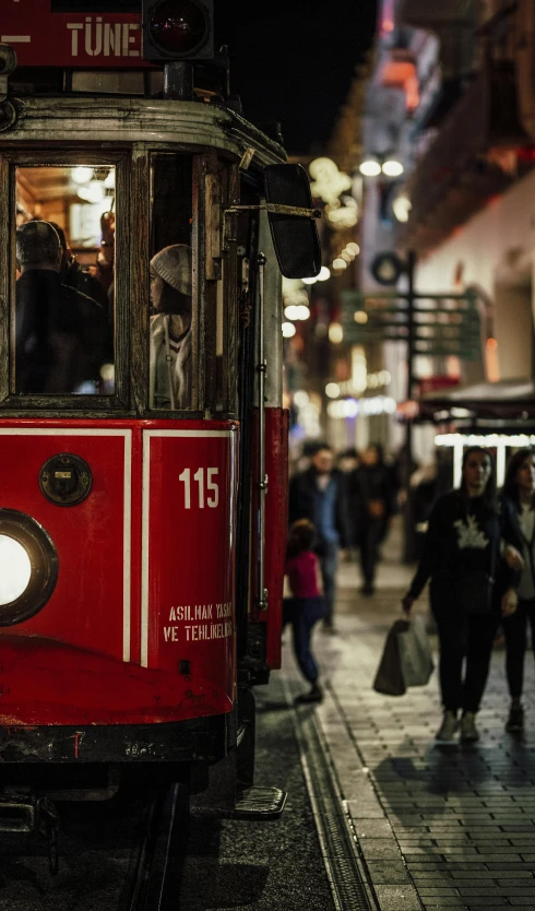 the trolly is driving through the city during night