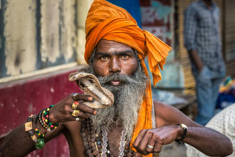 an indian man with a snake and a cigarette in his hand