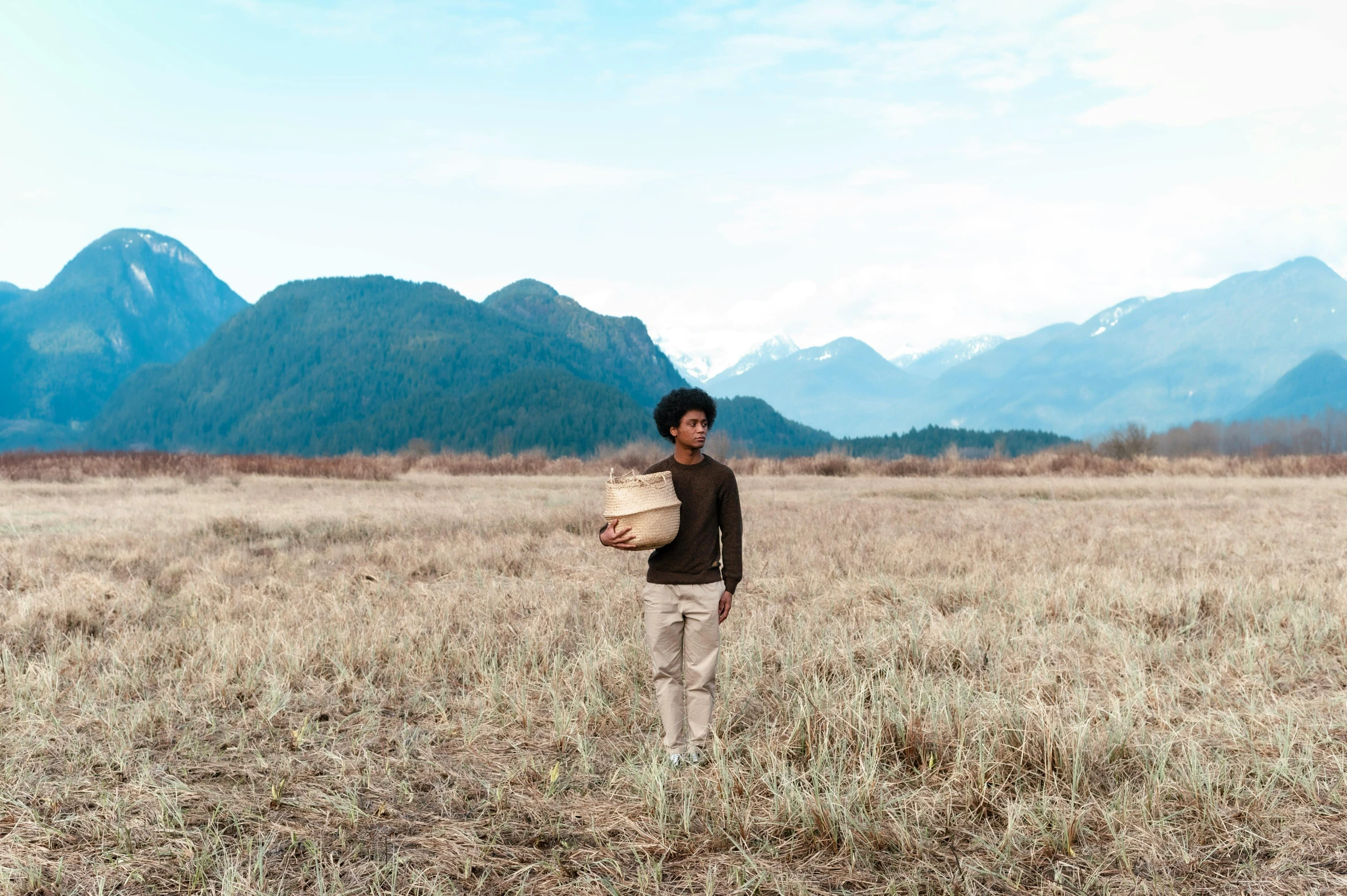 man standing with baskets on shoulders in field