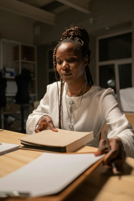 a woman is sitting at a desk and she is making notes