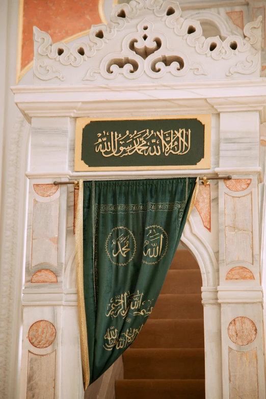 a white doorway that has green curtains and arabic writing on the top