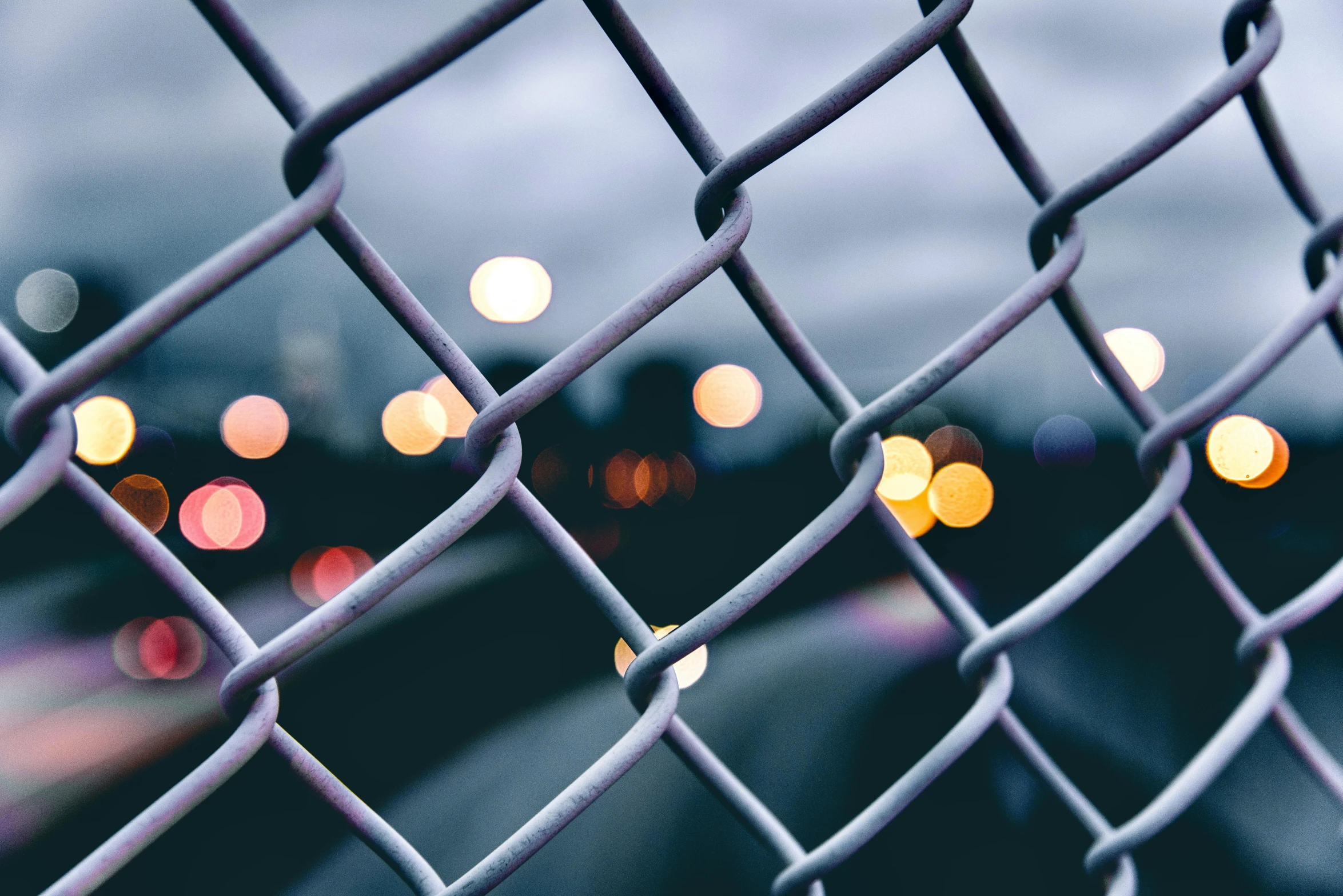 an image of a blurry night scene from behind a fence