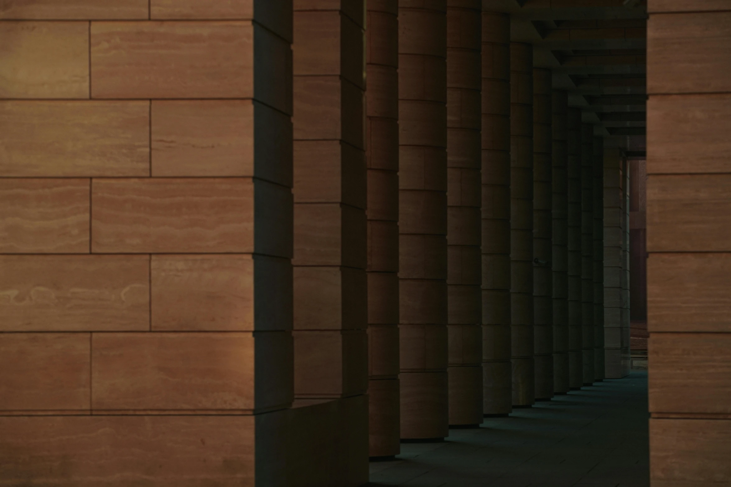 a brick wall with columns has a clock displayed on it