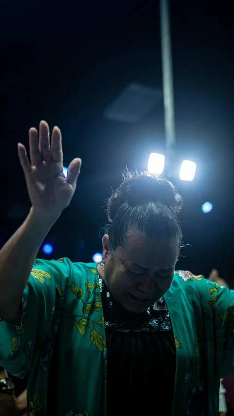 woman in green outfit holding her hands up and staring into the distance