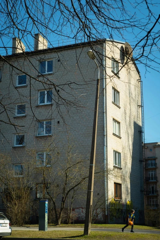 a building sits along a street behind a man holding an umbrella