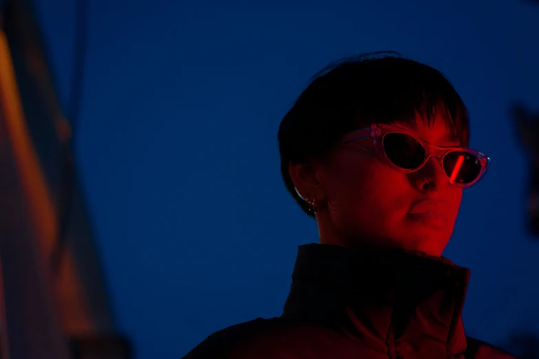 a woman with round sunglasses stands alone