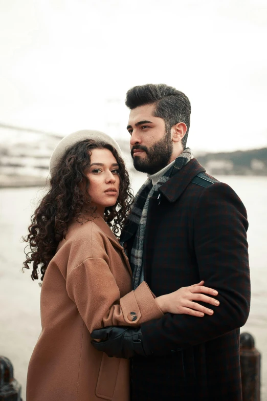 a man and woman standing on a pier by the water