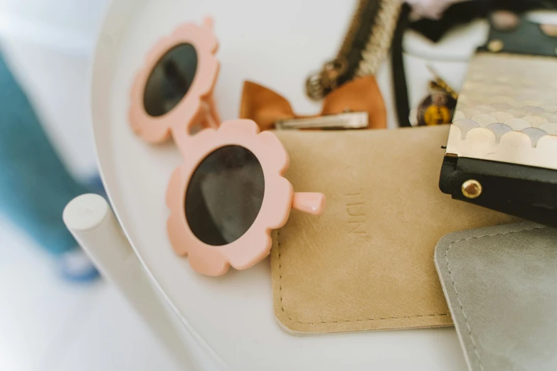 the pink sunglasses are placed on top of a leather wallet