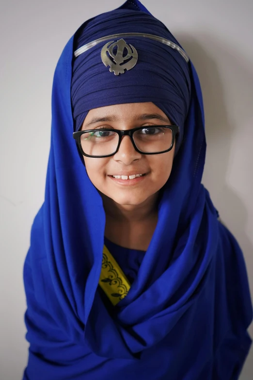 a young child in a blue headscarf smiles for the camera