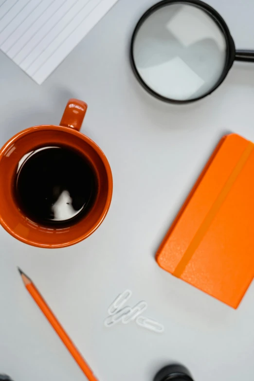 a cup of coffee, a note pad, and a pair of scissors are on the desk