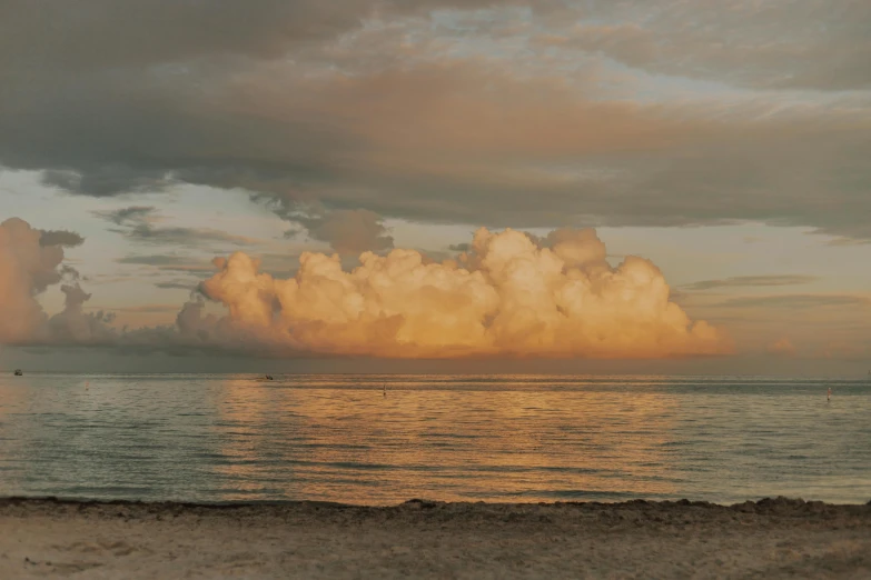 a very large cloud looms above the ocean with calm water