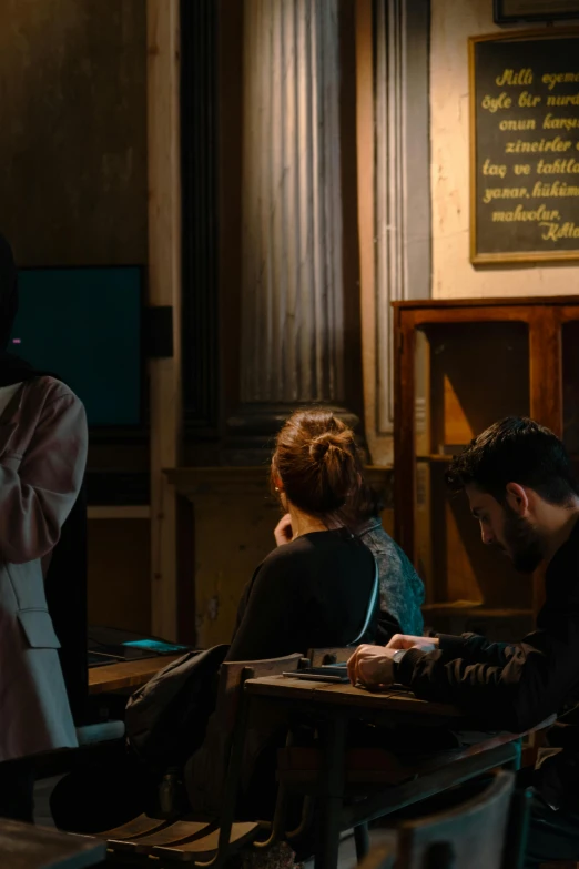 people sitting at tables and writing in a room