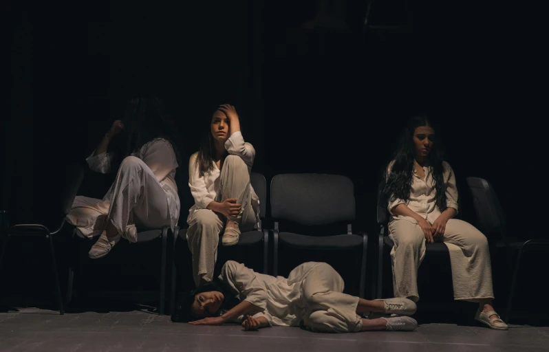 three women sit in chairs on the floor