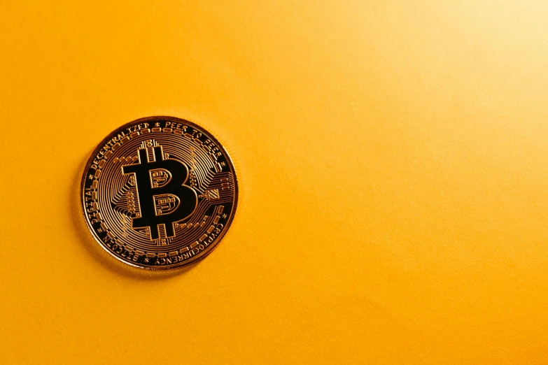 this gold bitcoin is on top of a yellow surface