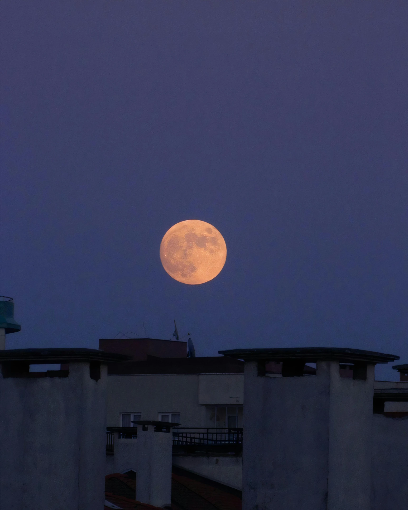 the full moon shining over rooftops and rooftop tops