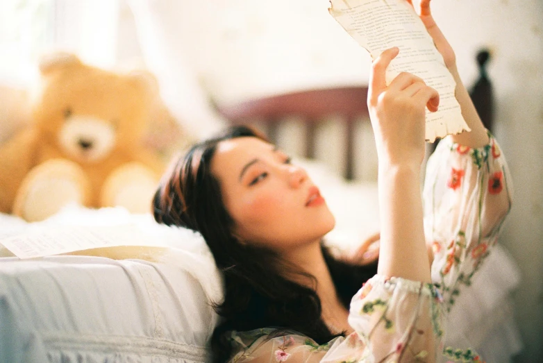 a girl reading a book and sitting on a bed