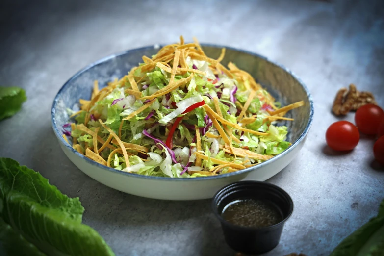 a salad in a bowl next to some tomatoes