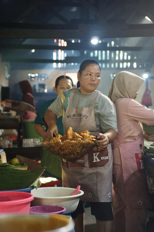 a woman is standing in a busy market selling food