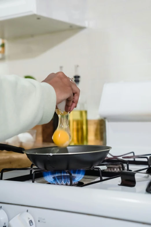 a woman stirring food in a large frying pan on the stove