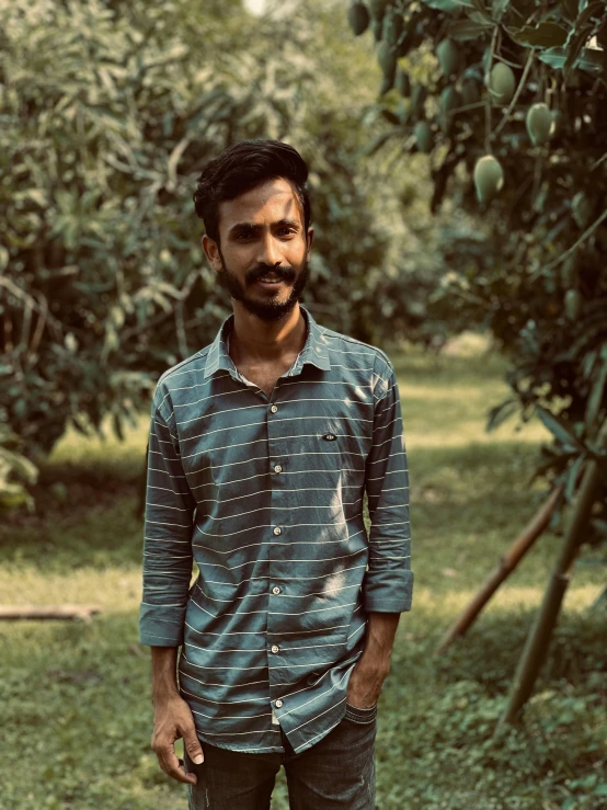 a young man standing under an olive tree with fruit on it