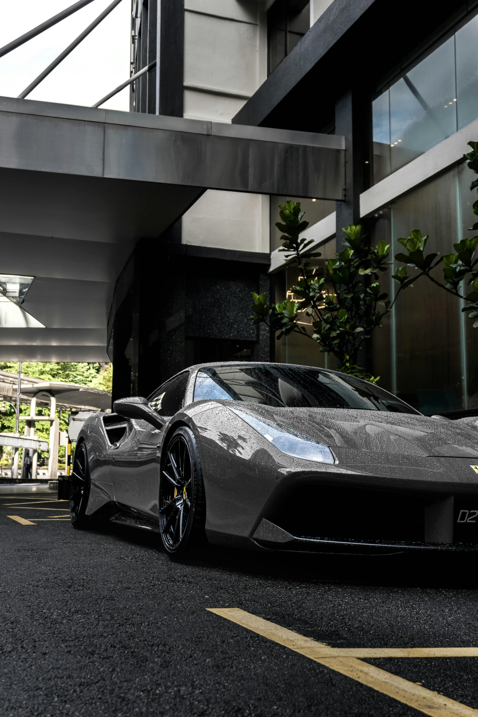 a metallic car is parked next to a very tall building