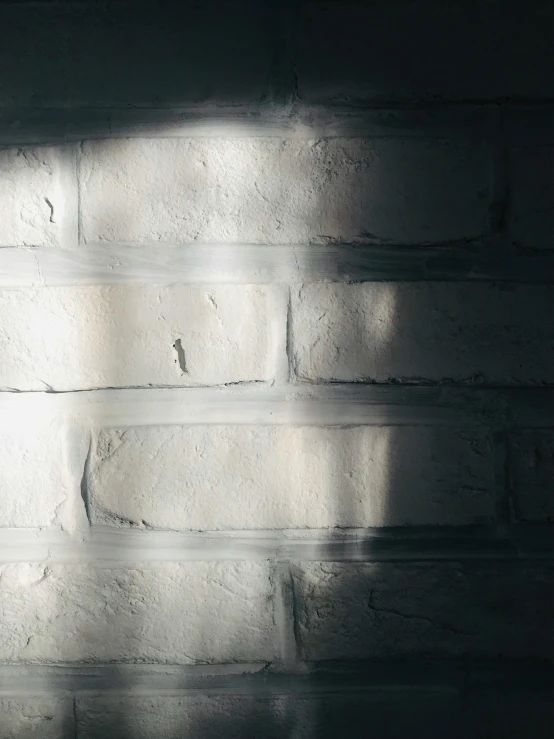 a light shines on a wall with white bricks