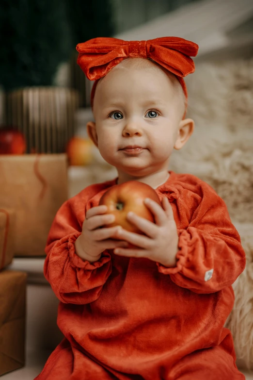 a small child holds a big apple and looks at the camera