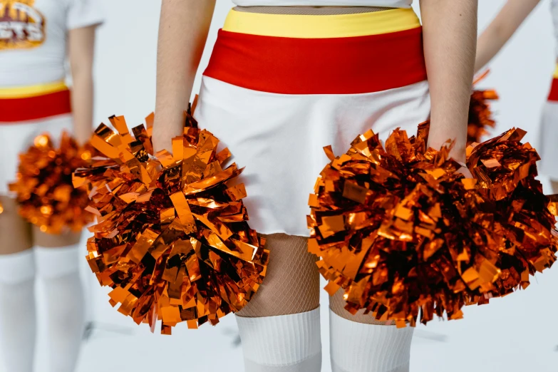 two women standing between each other with orange poms