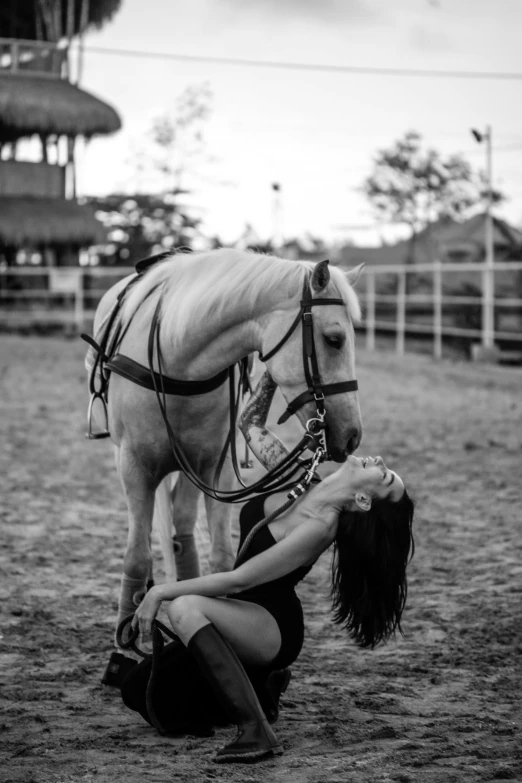 a woman bending down to pet a horse