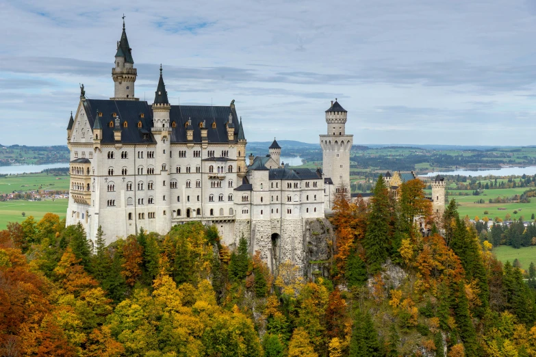 an elaborate castle in the fall with lots of trees and a large lake