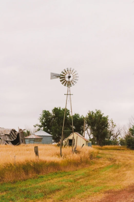 an old house sitting in a field behind a windmill