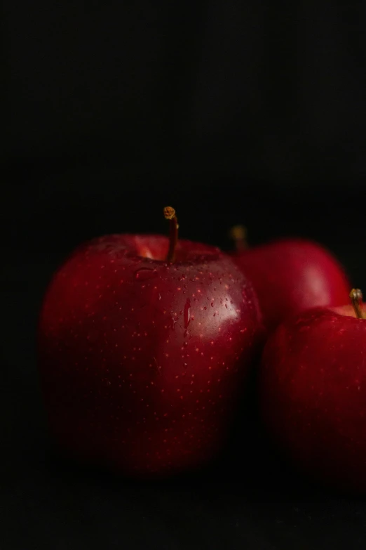 two apples sit close together in front of black backdrop