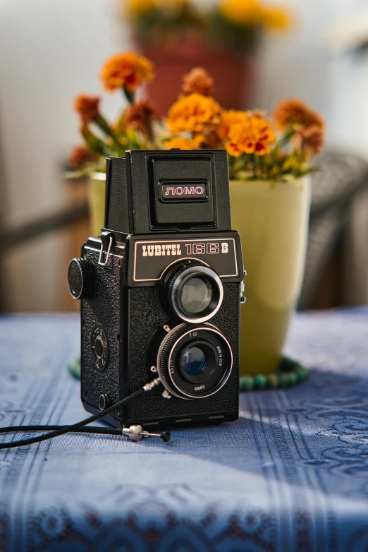an old camera sitting on a table next to some potted flowers