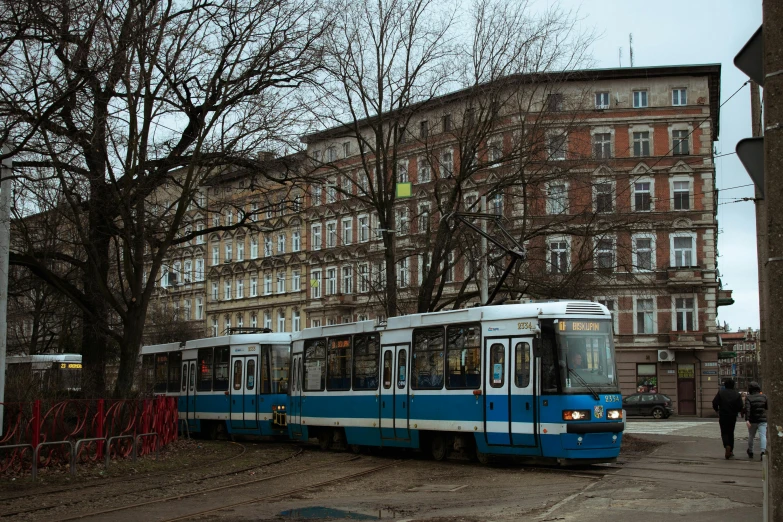 a blue and white train passing next to buildings