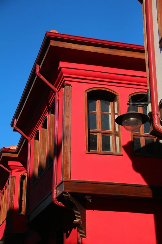 the side of a red building with a window and lantern