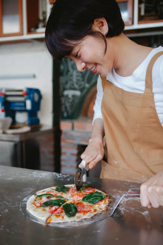 woman cuts up a pizza with a knife and scissors